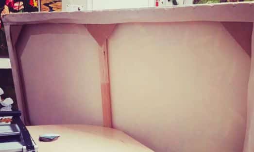 Interior of a pink-painted wooden crate or display case with curved panel corners, viewed from above.